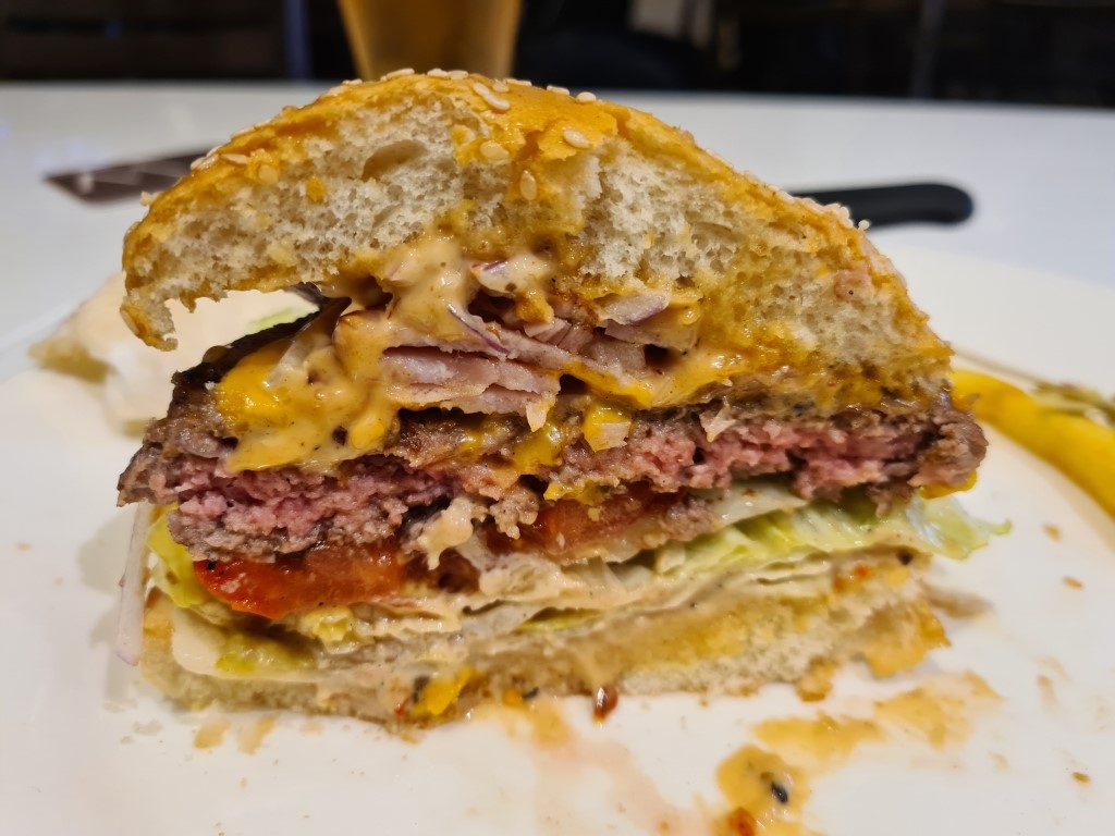 Wagyu Deluxe Burger cut in half at the Woolpack Hotel Parramatta showing juicy beef patty, melted cheese, bacon and toppings