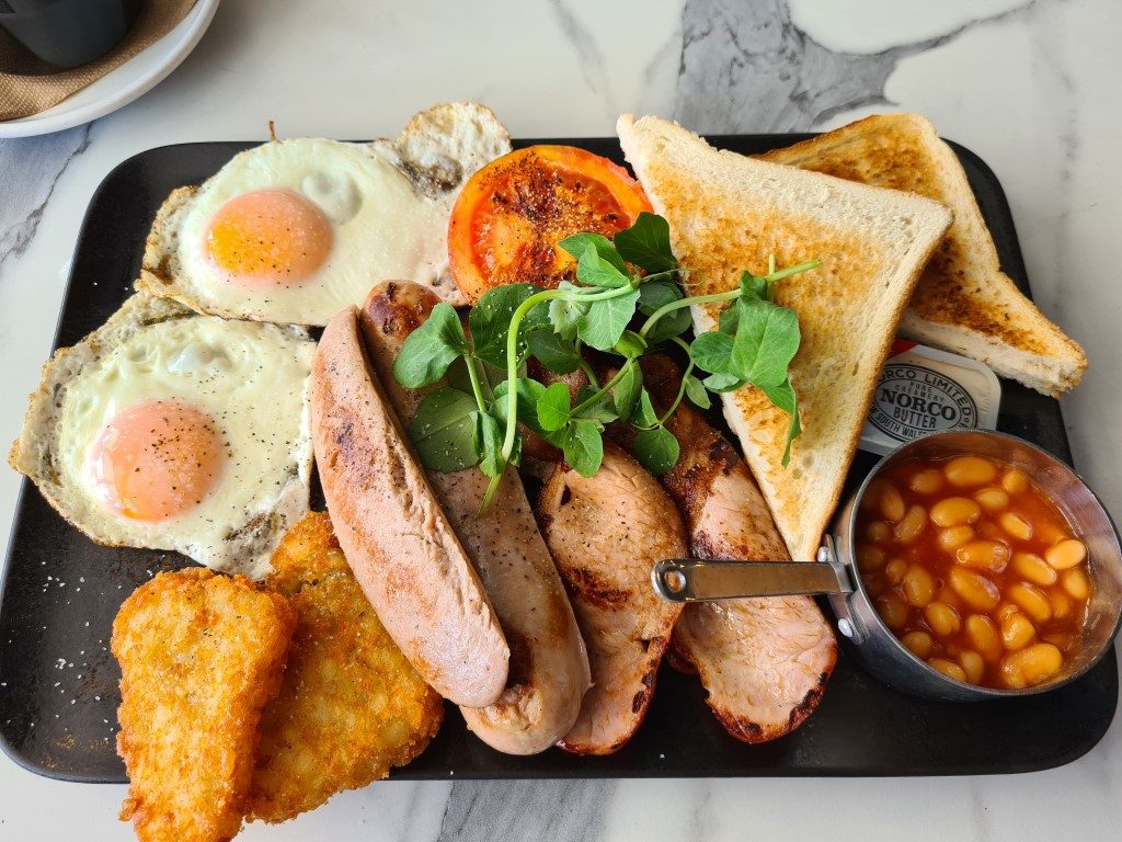 Massive Big Breakfast fry-up at Surfers Paradise Surf Life Saving Club – hearty Aussie plate with eggs, bacon, sausages, hash browns, grilled tomatoes, mushrooms, baked beans, and toast overlooking the beach on the Gold Coast"