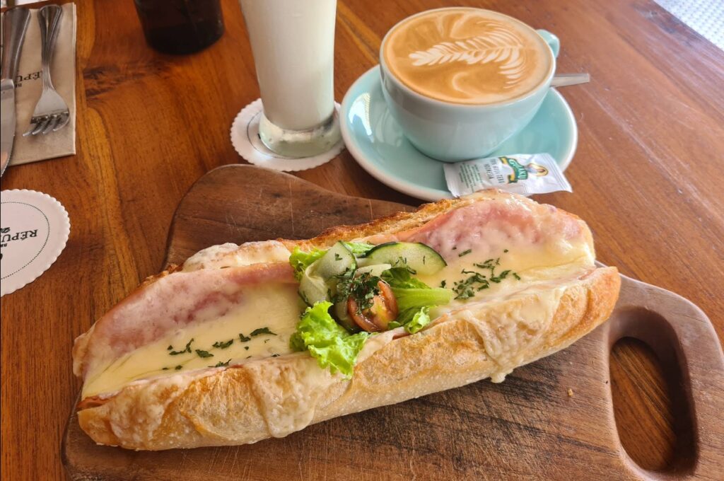 Ham and cheese baguette with melted cheese, served with flat white coffee and banana milkshake at Brasserie Republic in Sanur, Bali